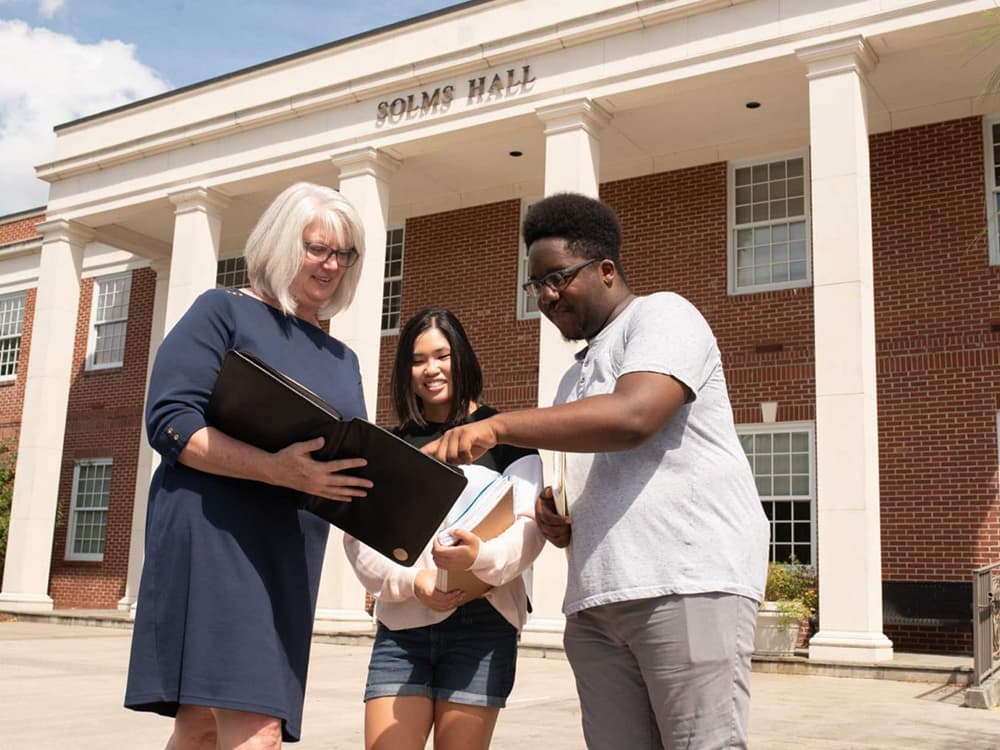 Two students talk with a professor outside of Solms Hall on the Armstrong Campus in Savannah