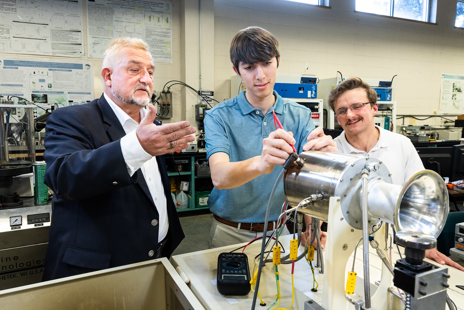 An instructor and students observing an engine.