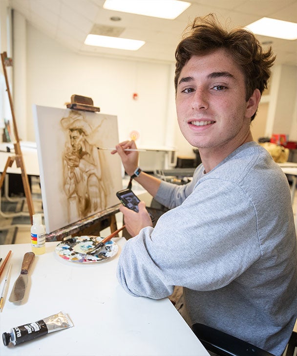 A College of Arts and Humanities student paints a picture of a cowboy in an art studio at Georgia Southern.