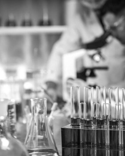 Black and white image of a laboratory with beakers and microscope.