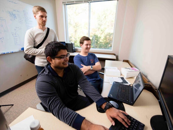 Two Georgia Southern Bachelor of Information Technology students watch a professional code and diagnose network issues during an internship