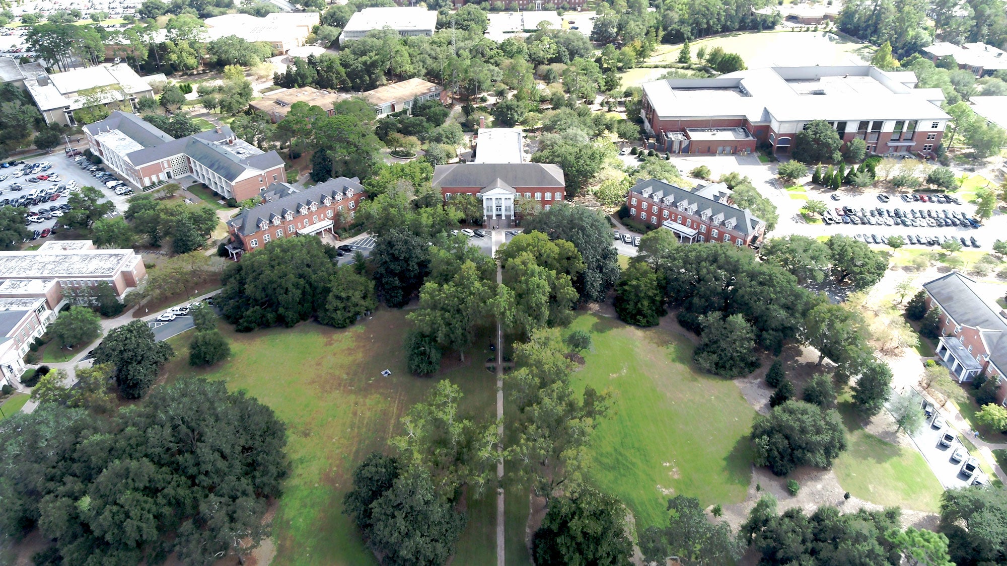 Two students in graduation caps stand in front of a building on one of Georgia Southern's campuses