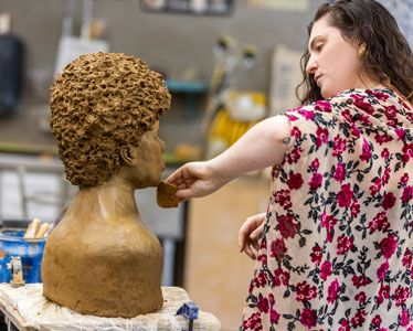 A student from Georgia Southern's College of Arts and Humanities sculpts a bust out of clay in an art studio