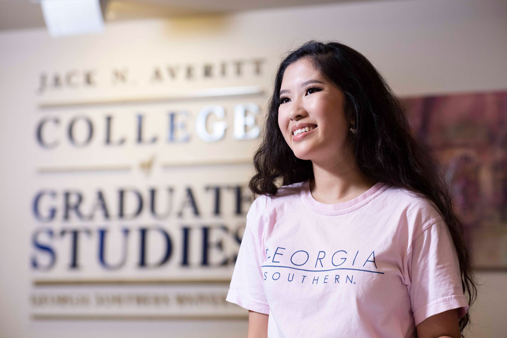 An ABM student stands in front of a sign for Georgia Southern's College of Graduate Studies