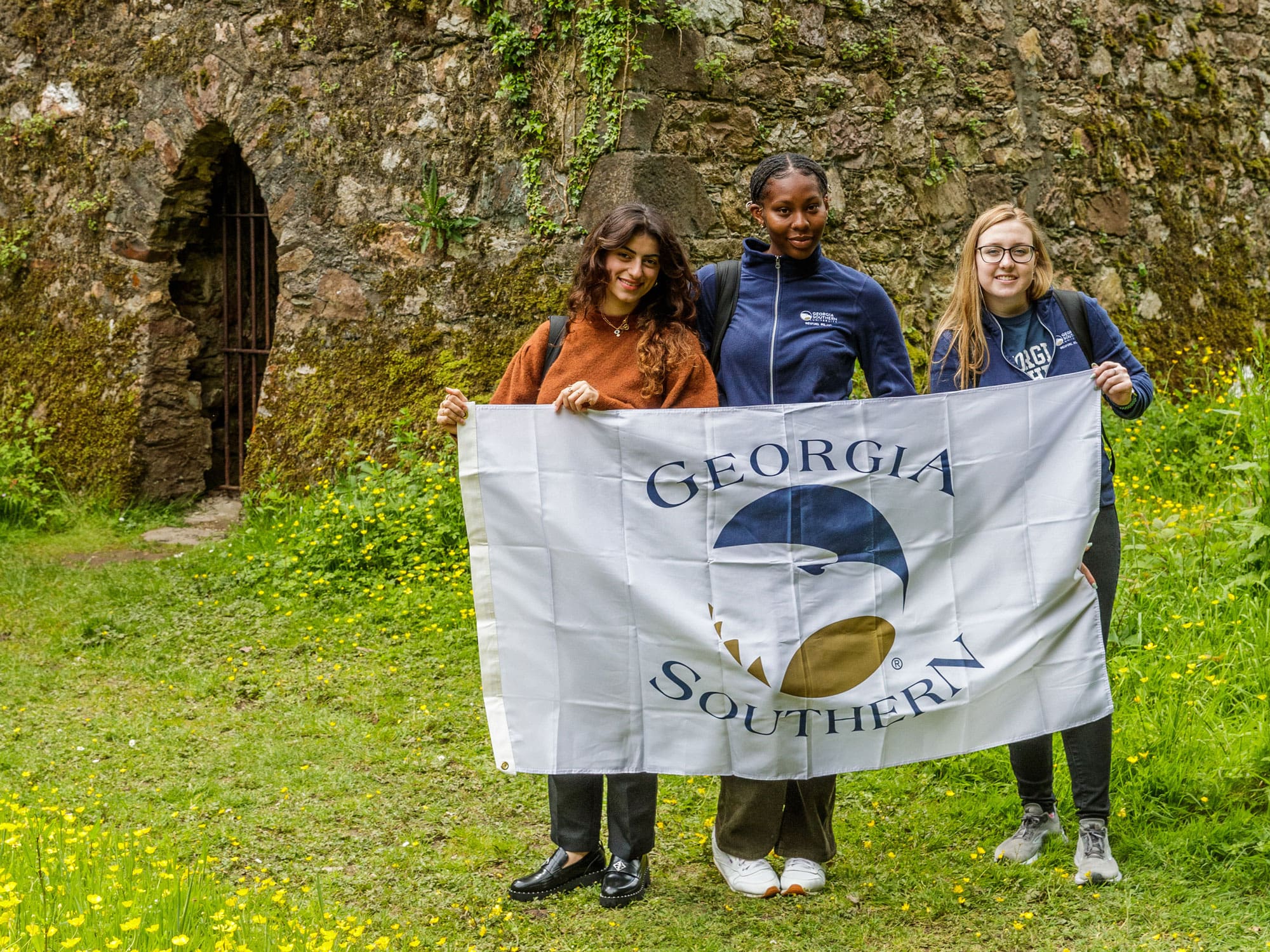 Three theatre majors hold a school banner outside Georgia Southern's Wexford, Ireland campus