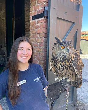 Georgia Southern B.S./B.A. in Biology alum Carson Moore, ‘22, stands next to an owl