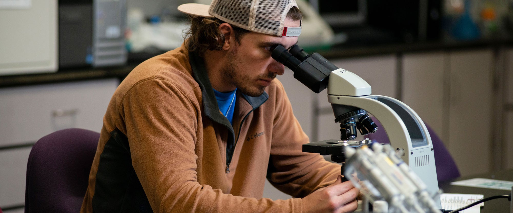 In a lab, a biology major at Georgia Southern examines slides with a microscope