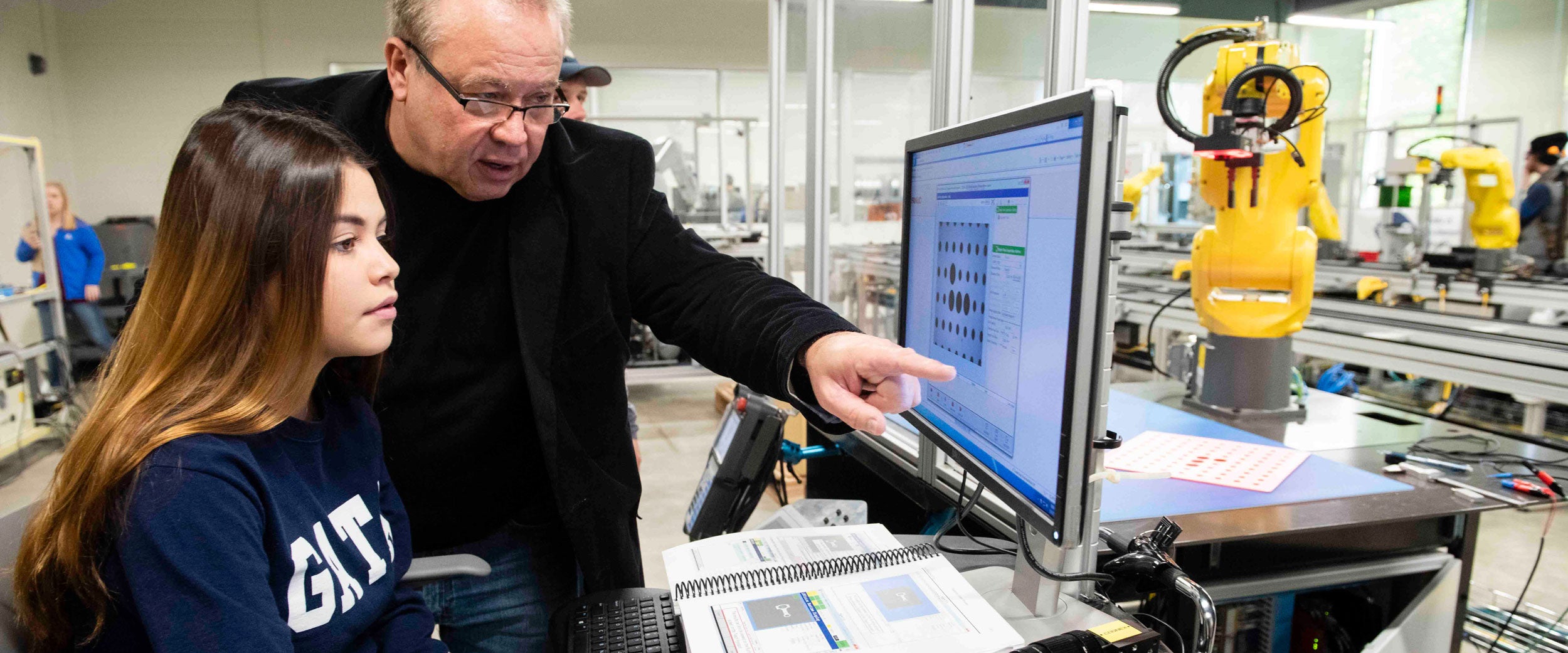 A professor points to a computer monitor while explaining a concept to a B.S. in Electrical Engineering student at Georgia Southern