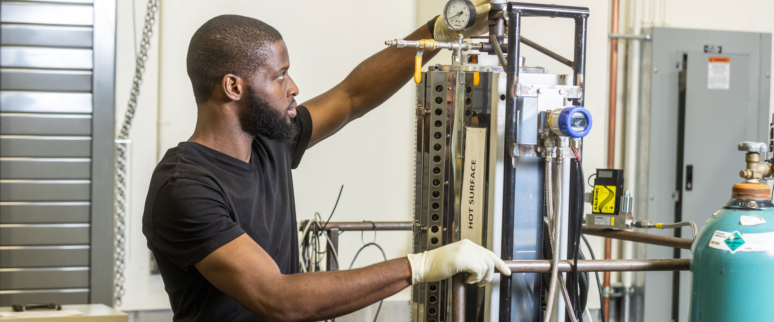 A B.S. in Mechanical Engineering student at Georgia Southern checks the pressure gauge on laboratory equipment