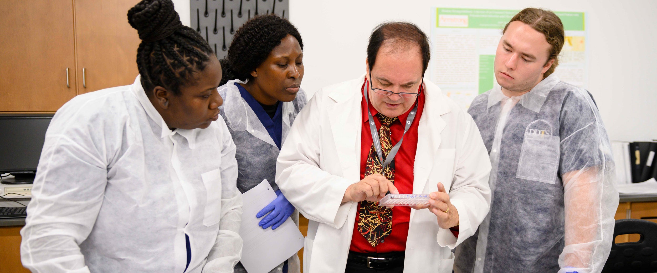 Three students in Georgia Southern's B.S. in Medical Laboratory Science program learn how to analyze samples from a faculty member