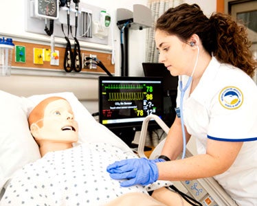 With a stethoscope and a manikin, a Georgia Southern BSN student practices taking vital signs in an on-campus simulation facility.