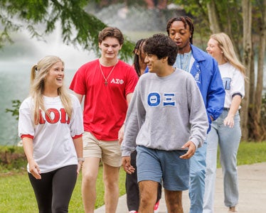 A group of BSN students wearing shirts with Greek letters walks through one of Georgia Southern's campuses.