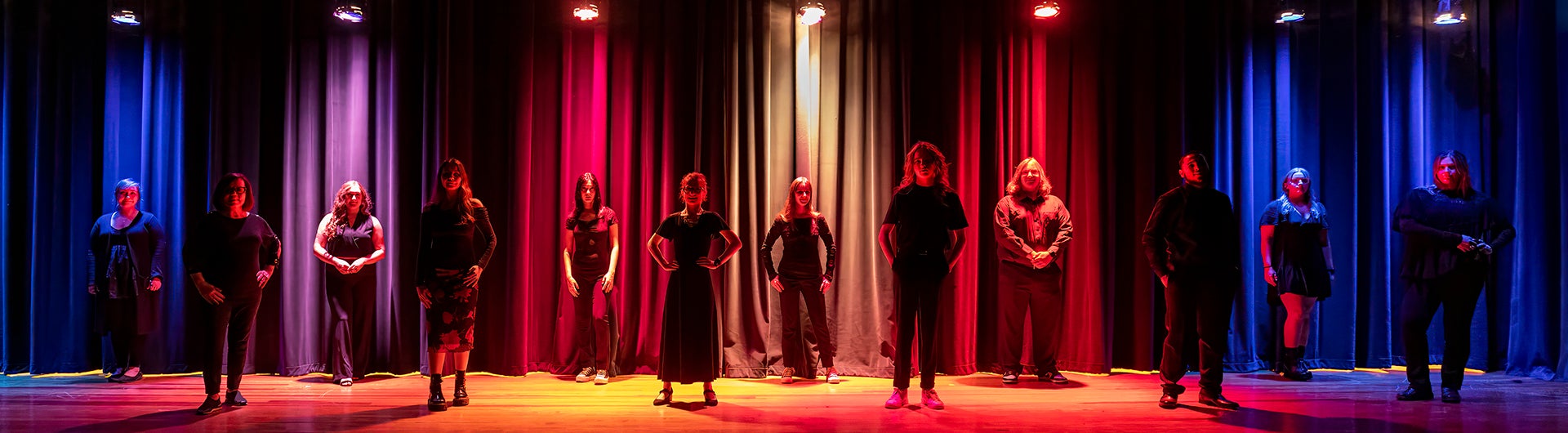 Georgia Southern College of Arts and Humanities students stand in a staggered row for a stage production involving colorful lights