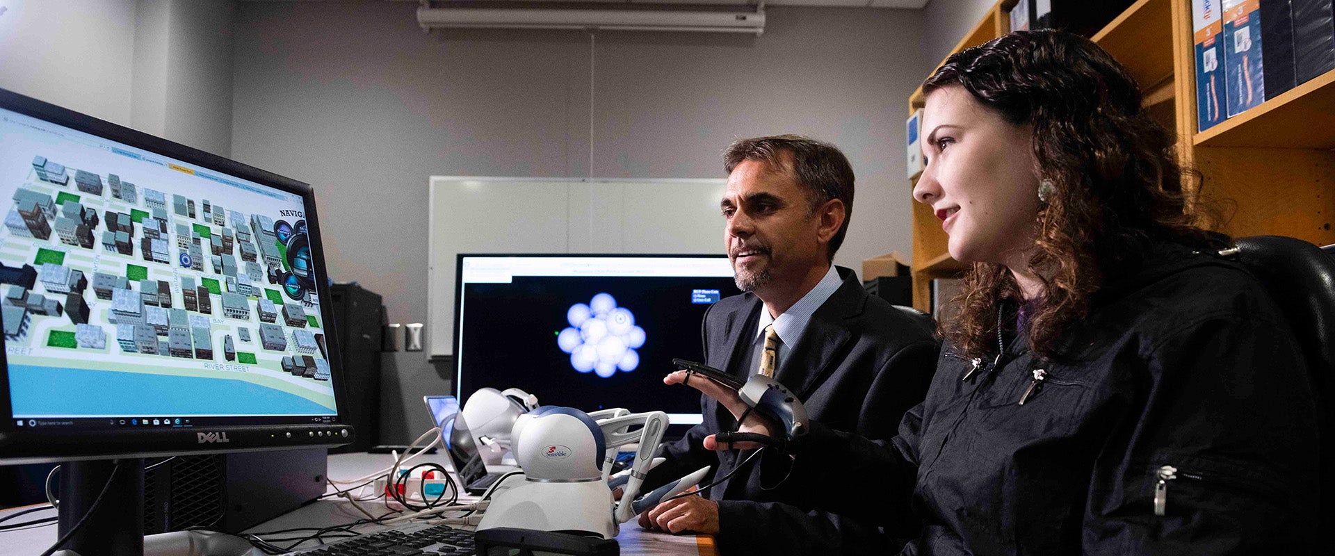 A student in Georgia Southern's College of Engineering and Computing explains their civil engineering project displayed on a computer screen to a faculty member