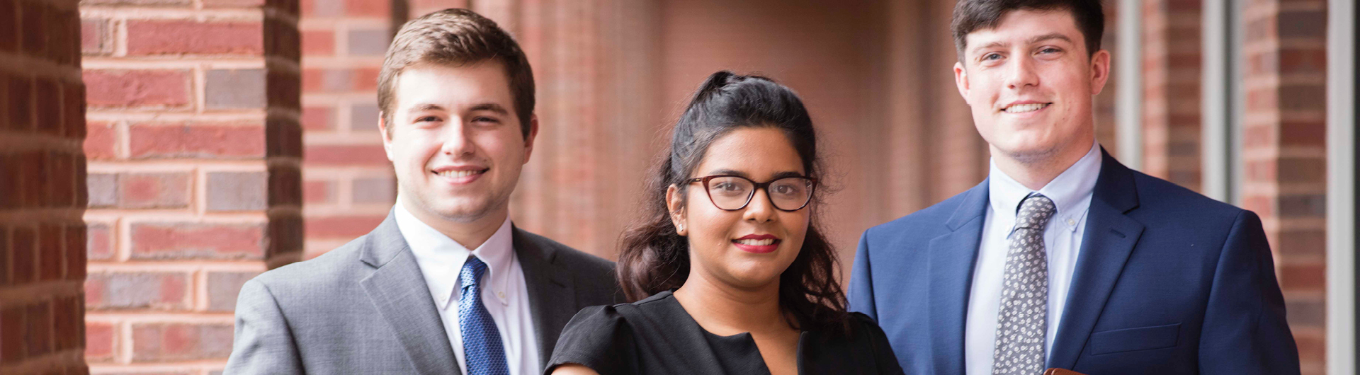 Three students from Georgia Southern's Online MBA program stand outside a brick building before a job fair