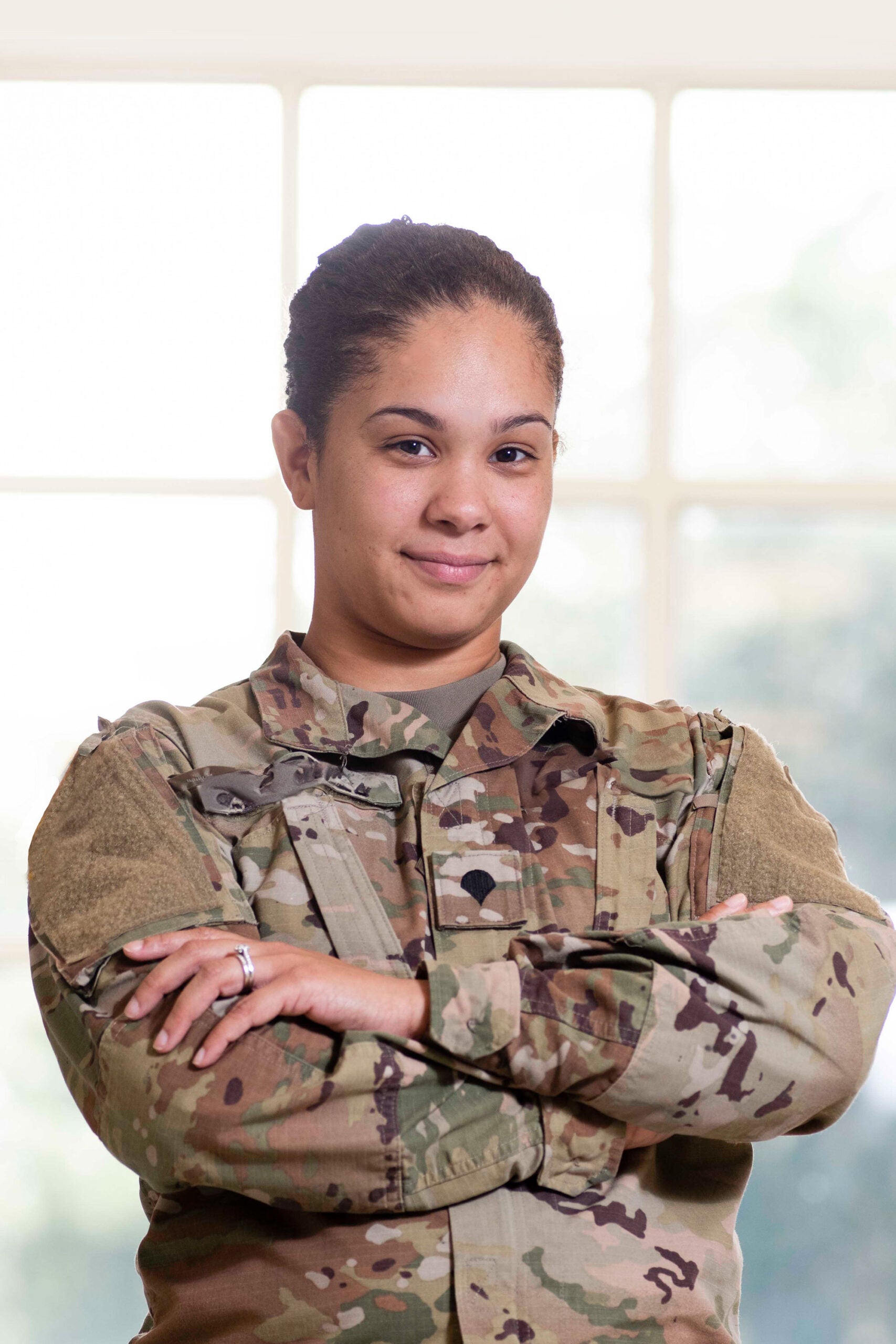 Military student in uniform standing with arms crossed.