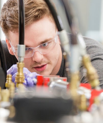 A Georgia Southern College of Engineering and Computing student wearing safety glasses adjusts connection points for an experiment