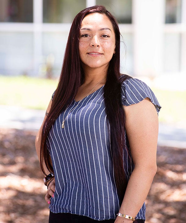 A Georgia Southern graduate student stands outside with one hand on their hip.