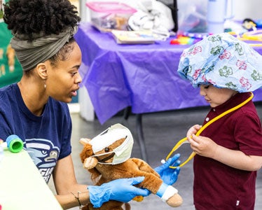 During a community outreach initiative, a student from Georgia Southern's Accelerated BSN program uses a stuffed animal to introduce the basics of medical care to a child.