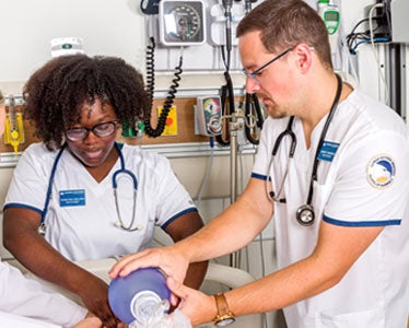 Two students from Georgia Southern's Accelerated BSN program practice patient care techniques in a clinical simulation space