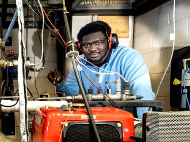 A B.S. in Construction Management student from Georgia Southern wears hearing protection while standing near pipes and various tubes.