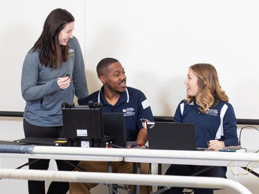 Three students from Georgia Southern's B.S. in Kinesiology, Exercise Science program meet up to talk athletic performance and body composition in a training space.