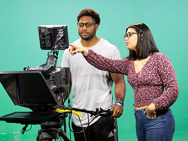 Two Georgia Southern Department of Communication Arts students operate filming equipment in an on-campus studio.