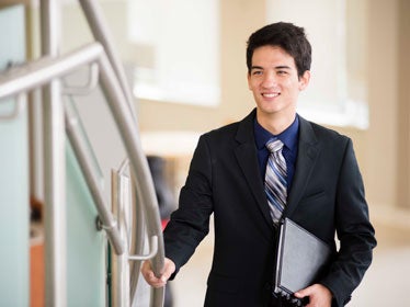 A Georgia Southern Department of Public and Nonprofit Studies student in a suit walks up a set up stairs before a presentation