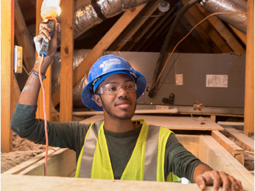 A student from Georgia Southern's Department of Civil Engineering and Construction wears a hard hat and hi-vis vest on a simulated building site