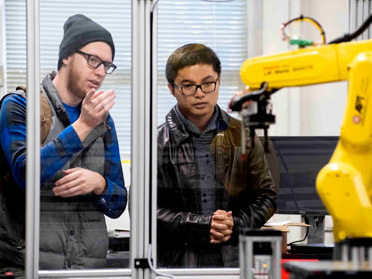 Two students from Georgia Southern's Department of Manufacturing Engineering practice operating a robotic arm