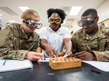 Three students from Georgia Southern's Department of Military Science wear safety goggles to conduct an experiment