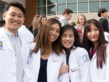 A group of students from Georgia Southern's Pre-Health Professional Programs stands outside in lab coats