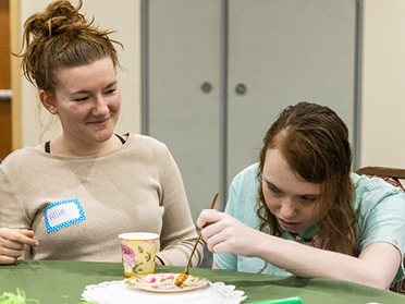 Participating in a community outreach assignment, a student from Georgia Southern's M.S. in Psychology, Behavior Analysis program watches someone paint dishes.