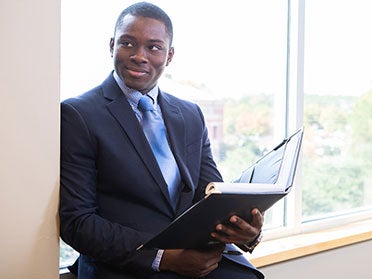 Wearing a suit, a student in Georgia Southern's Department of Finance reviews a folder containing financial documents.