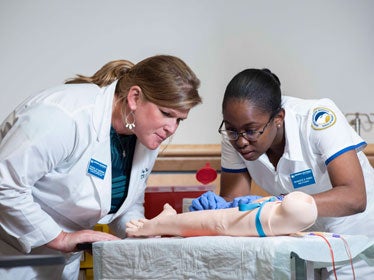 With guidance from an instructor, an RN to BSN student at Georgia Southern uses an intravenous practice arm to learn to take blood.