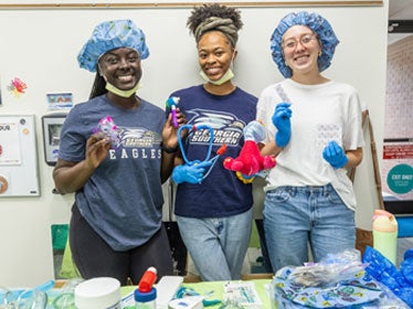 Three nursing students at Georgia Southern wear gloves, hair nets and masks for a campus outreach program.