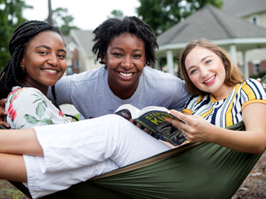 Three Georgia Southern students lounge in a hammock outdoors on Georgia Southern's Armstrong campus in Savannah