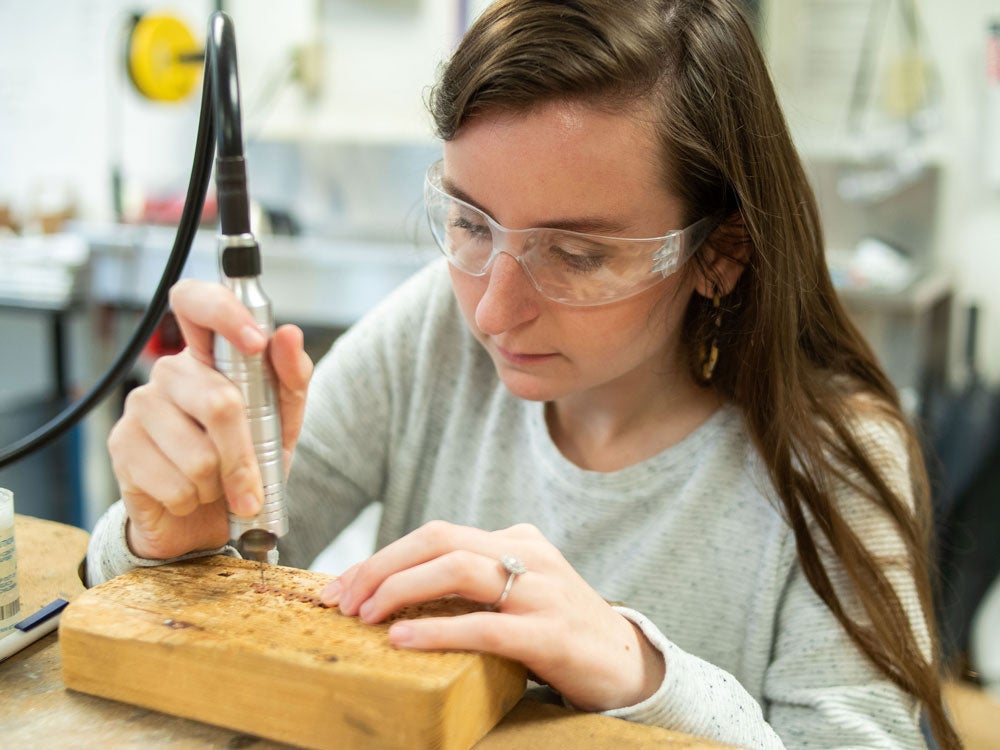 Georgia Southern art student in studio classroom; wood engraving tool 3-D art