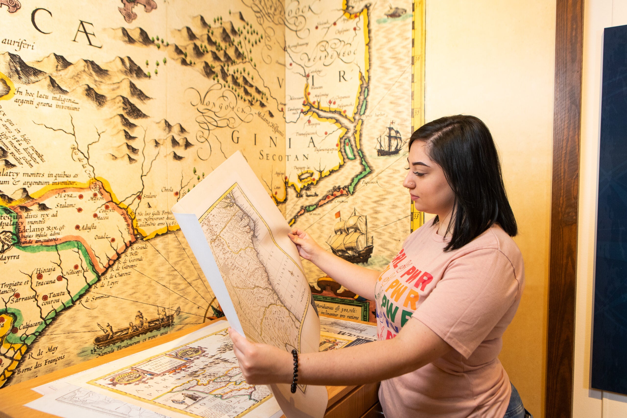 Georgia Southern student inside of an academic building where there is a large map on the wall. Student is also holding a map and looking at it.