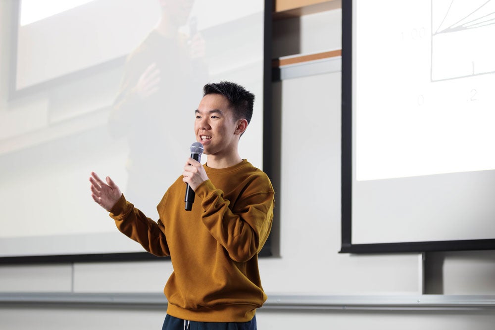 Georgia Southern Student holding a microphone, giving a speech in front of live audience