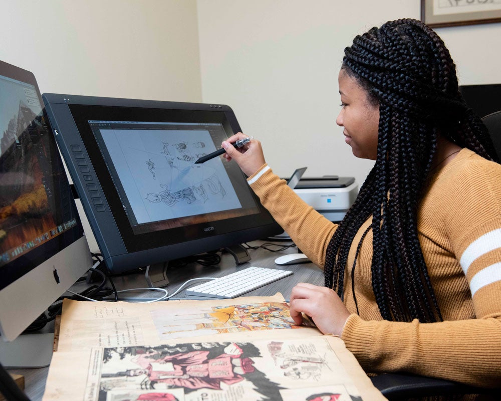 Georgia Southern student working on a digital design, using a stylus on a screen, in an art classroom environment.