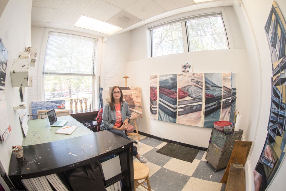 art student in well lit studio classroom, multi-media art displays