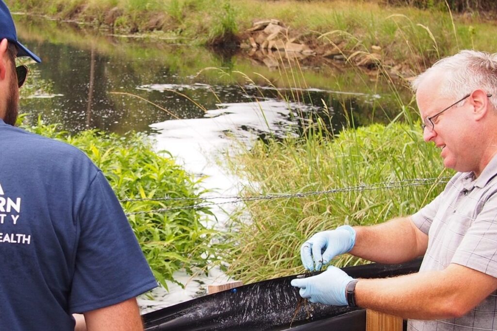 Water researchers sluice materials on the banks of a pond or waterway.