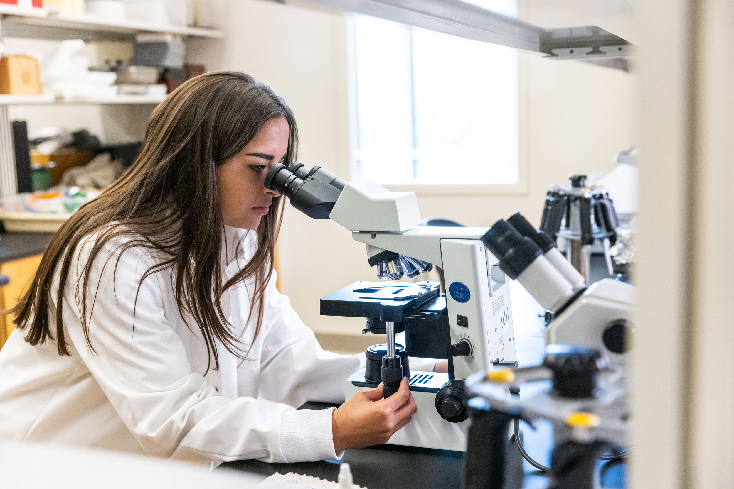 Georgia Southern student in science lab looking into microscope.