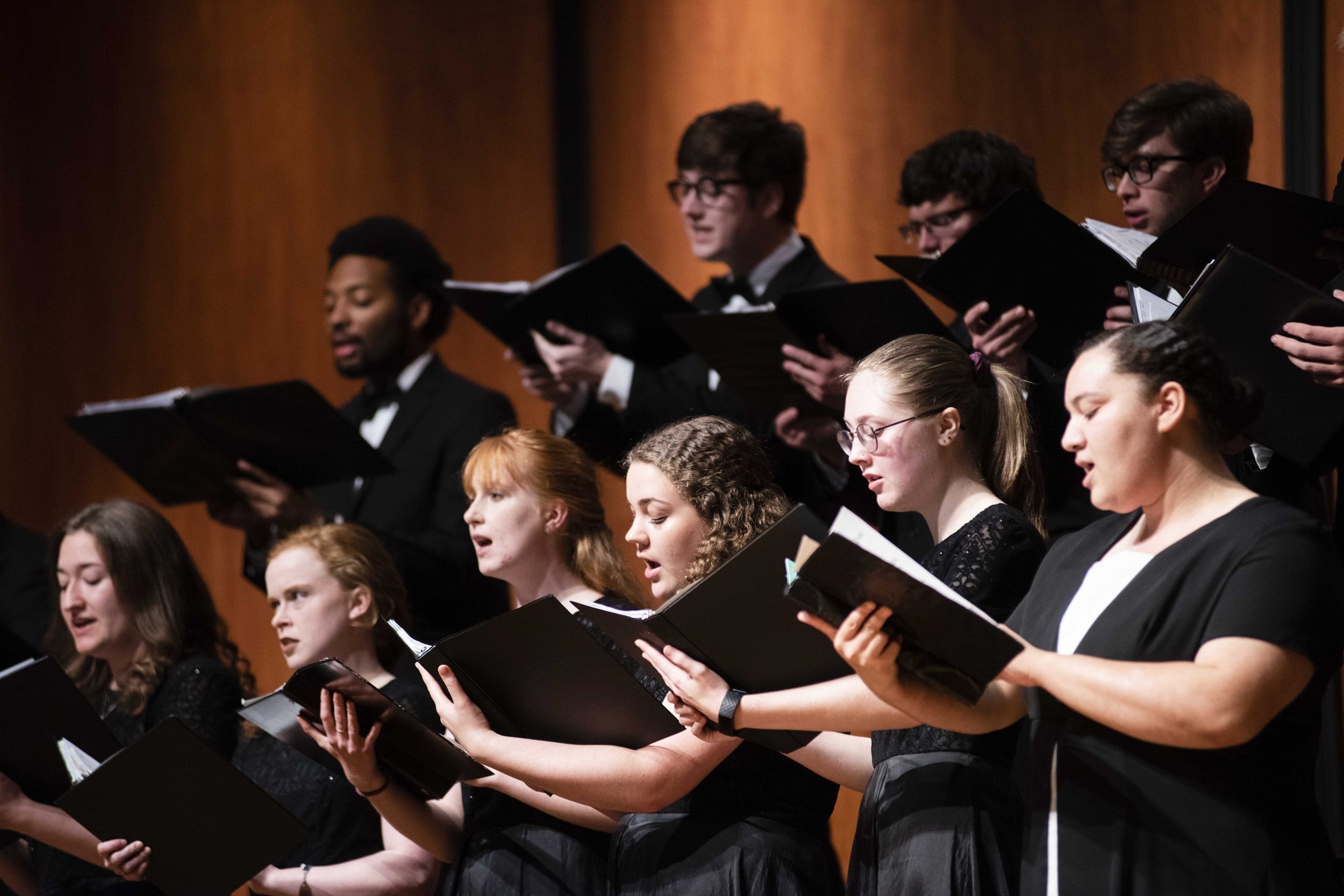 Group of diverse Georgia Southern students dressed in formal clothes singing in a choir performance.