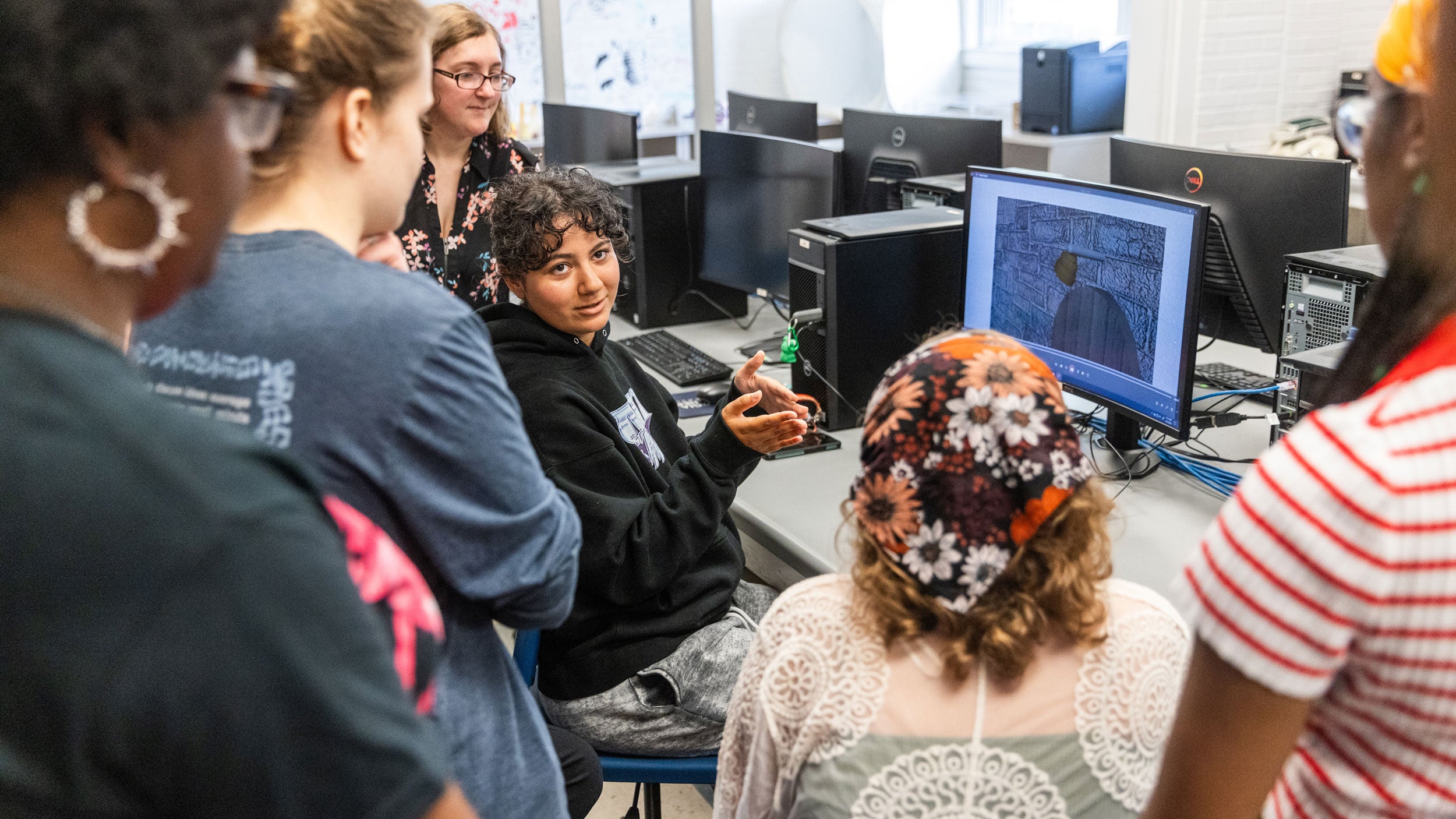 Georgia Southern animation students gathered around a computer, working with an animation software.