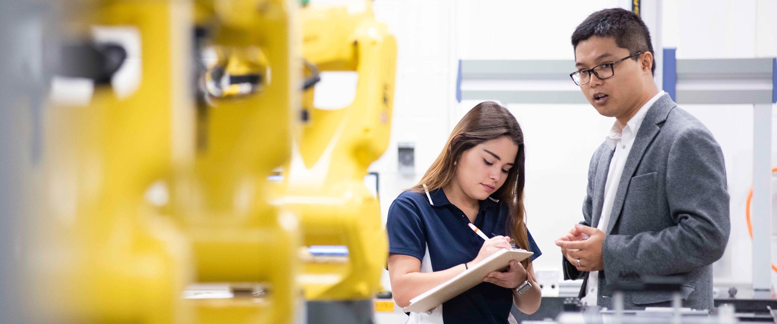 Georgia Southern student takes notes as a professor lectures in a manufacturing engineering lab.