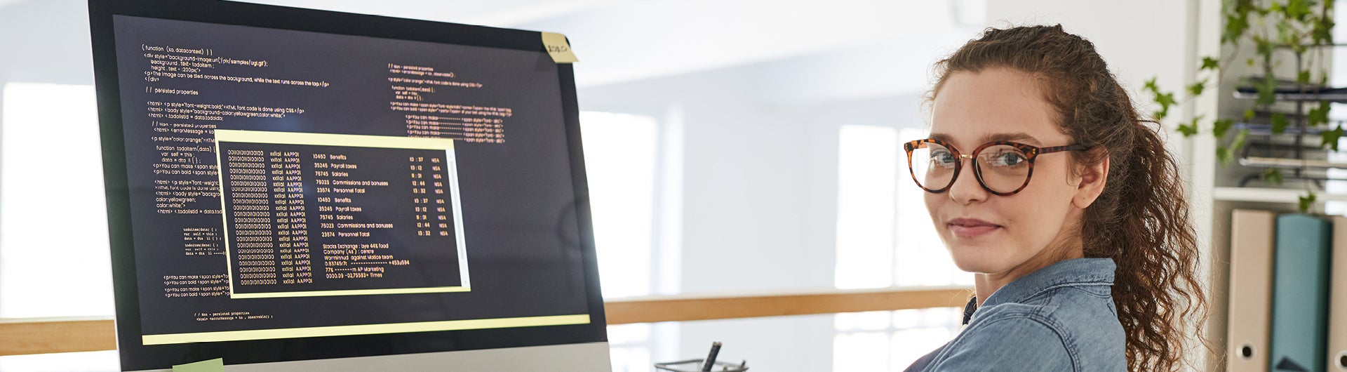 A student in front of a computer showing code.