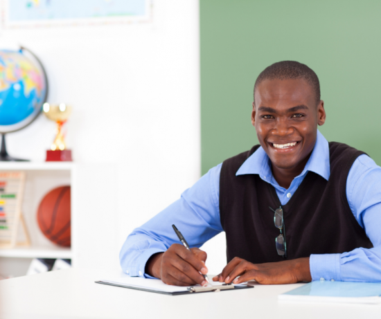 A young African-American man is writing at a desk with classroom elements (a globe, a trophy, a basketball, an abacus) in the background.