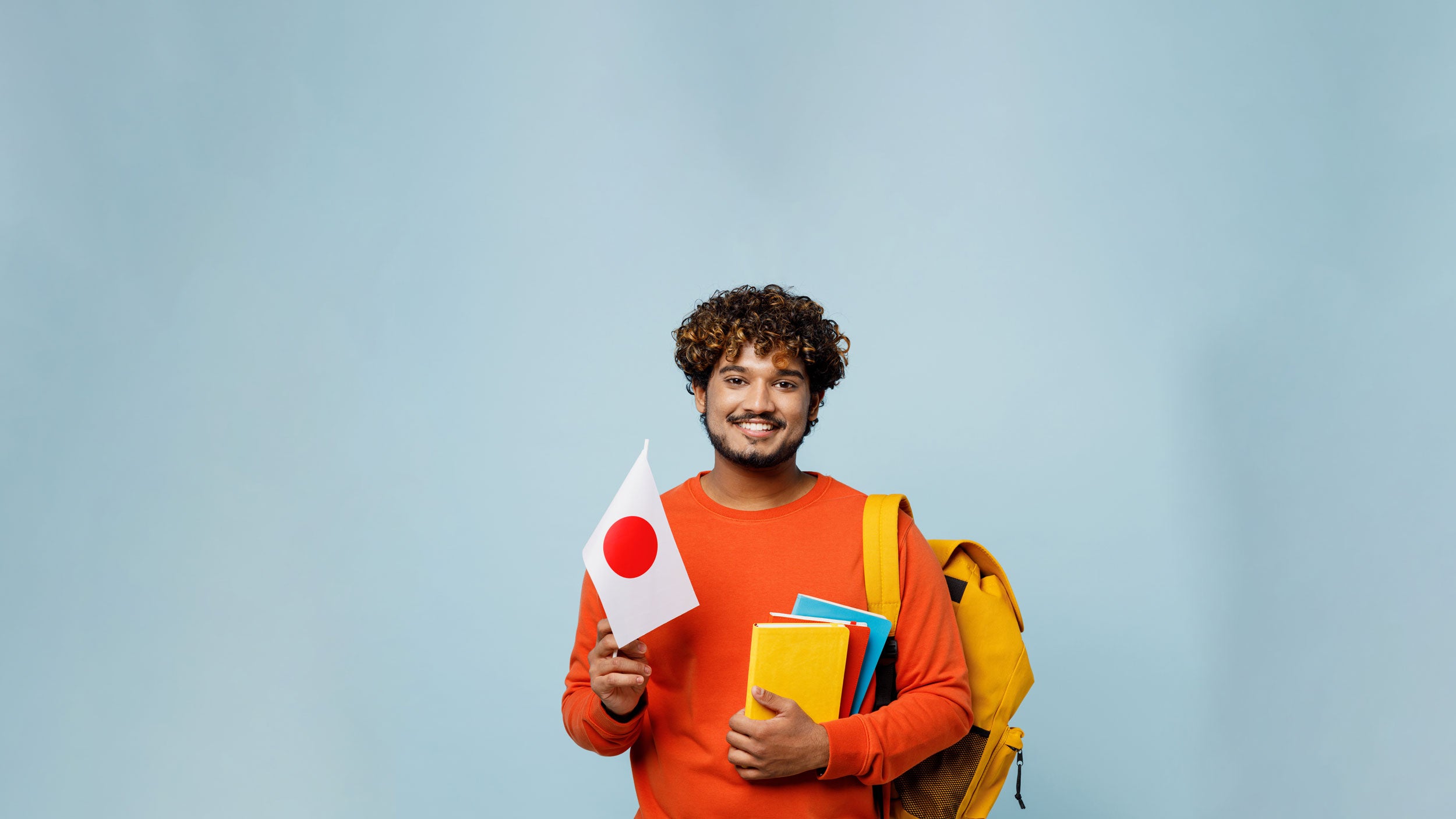 Georgia Southern student holding notebooks in one hand and a Japanese flag in the other. Student is smiling and looks eager to learn.